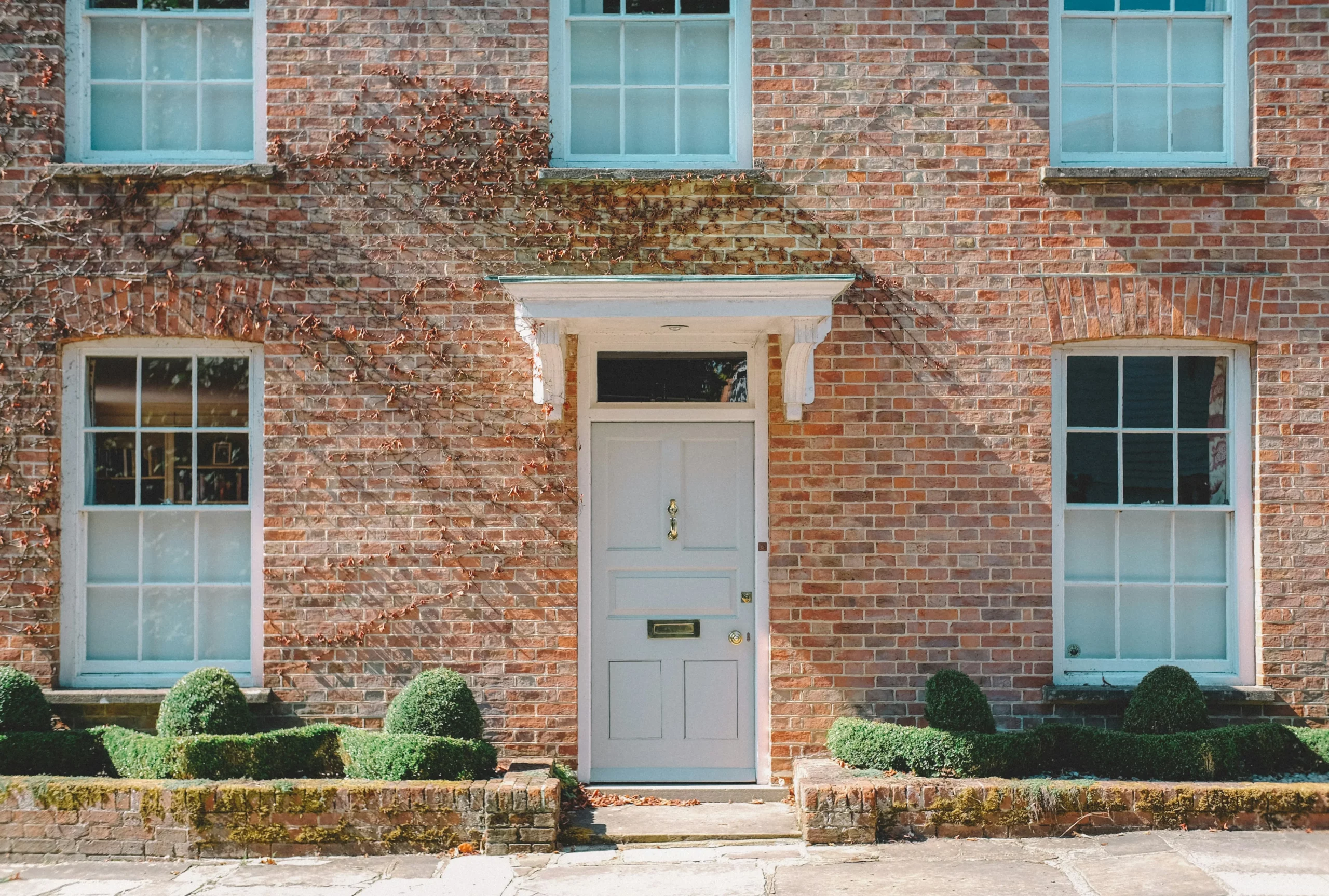 Traditional brick townhouse exterior with pale blue-framed windows and a white front door — UK residential property